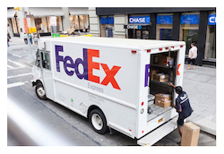 FedEx truck with open door and worker unloading boxes