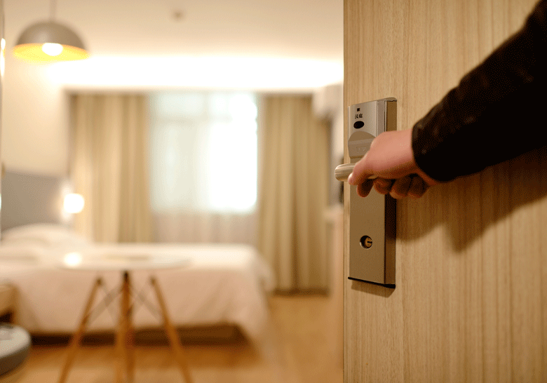 Close-up shot of a hand opening the door to reveal the interior or a hotel room